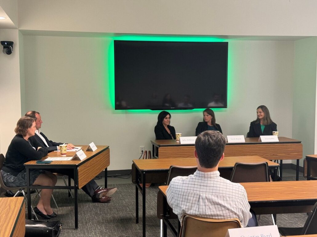 A photo of the appellate law panel session is depicted. Three panelists are pictured seated at a table, and a number of other individuals are seated at tables in the room.